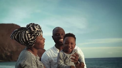 Happy African family having fun on the beach during summer holidays - Parents love concept
