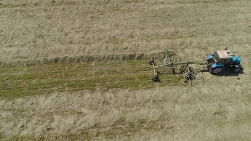 Trator com Rake Tedders no campo da fazenda