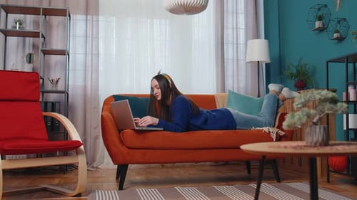 Young Woman Using Laptop Relaxing on Sofa