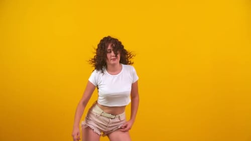 Stylish Woman Dancing in Studio on Yellow Background