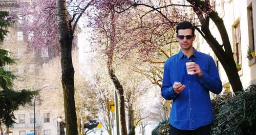 Man using mobile phone while having coffee in park 4k