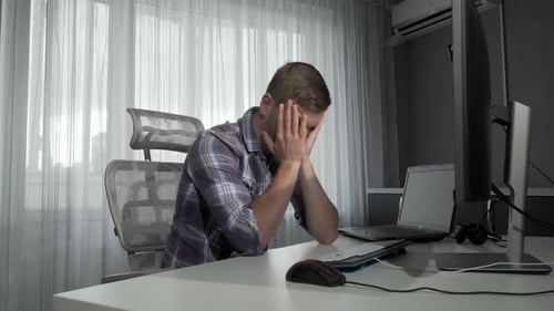 Verärgerter männlicher Freelancer sitzt vor seinen Computern