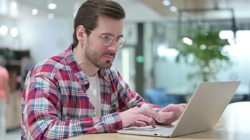 Young Adult Typing on Laptop Celebrates Success