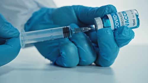 Spritze mit Nadelfüllung mit transparenter Flüssigkeit. Mit Impfstoff oder anderen Medikamenten gefüllte Durchstechflasche