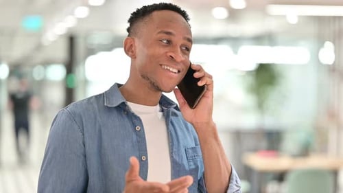 Young Man Chatting on Smartphone in Office