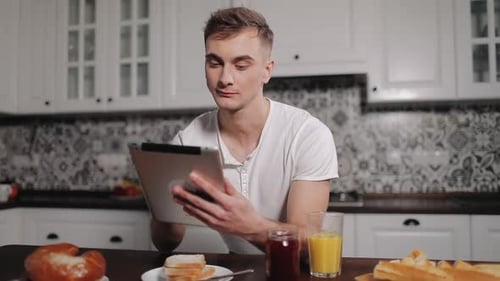 Pensive Man Using Tablet in Kitchen