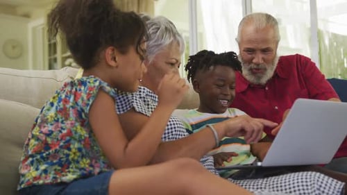 Grandparents and Grandchildren Look at Laptop at Home