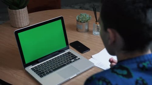 Closeup Back View Shot of Young Man Having a Video Call on the Laptop with Green Screen in the Home