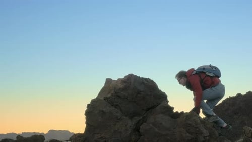 A Man Climbs a Mountain Peak and Raises His Hands Triumphantly To the Sky