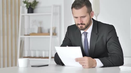 Businessman Celebrating Success While Reading Documents in Office