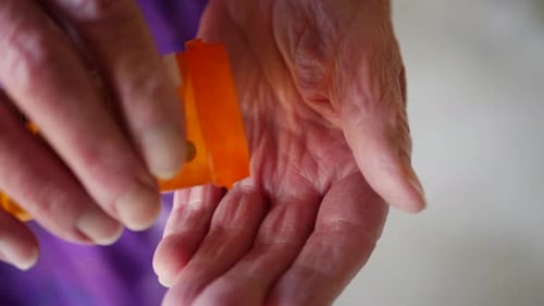 Elderly Hand Pours Medicine From Pill Bottle