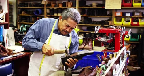 Craftsman Repairs Shoe with Hammer in Workshop