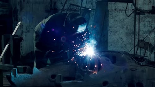 Soldador de la industria pesada suelda piezas metálicas para la reparación de automóviles