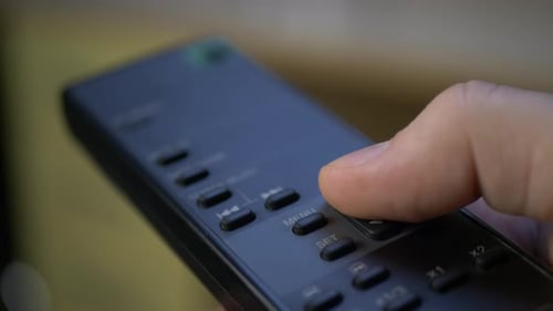 La mano presiona el botón B en el televisor con control remoto