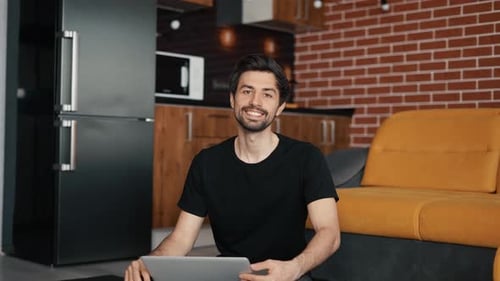 Man Uses Laptop Smiling in Modern Apartment