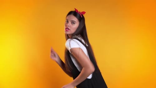 Young Woman Dancing Energetically on Yellow Background