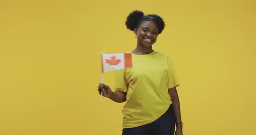 Smiling Woman Waving Canadian Flag on Yellow