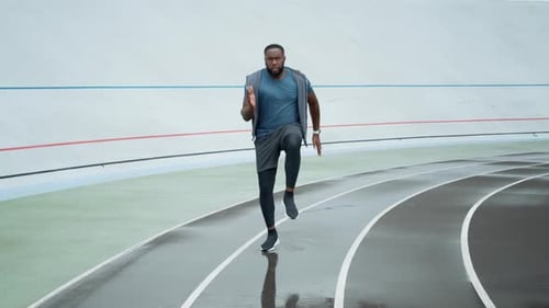 Sportsman Doing High Knee Taps During Workout, Guy Training on Stadium Track