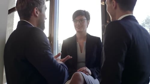 Business People Discuss Strategy in Office Window