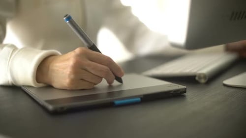 Hand Using Stylus on Tablet at Desk