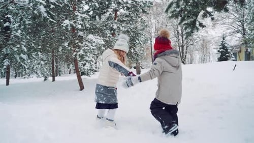 Los niños se toman de la mano en el patio y corren juntos en una colina nevada