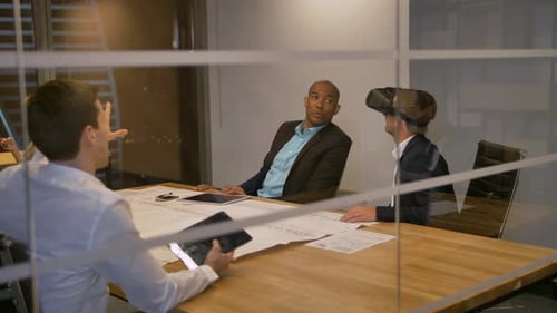 Male in VR Headset Looking at Objects in Virtual Reality with Colleagues