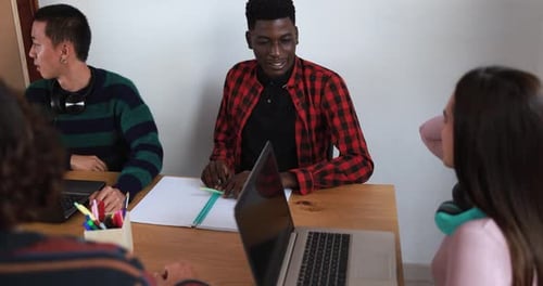 Multiracial students reading books and using laptop while studying together - School concept