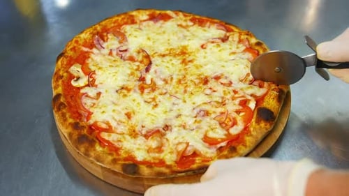 Chef cutting freshly baked pizza. Close up hand of chef baker cutting pizza at kitchen