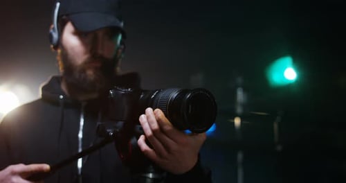 Bearded Person Adjusting Lens on a Digital Camera