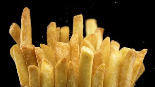 Adding Salt to Crispy French Fries Close Up