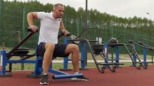 Man Trains in the Air on a Simulator Does Triceps Exercises