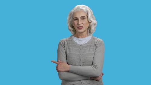 Smiling Mature Woman Pointing with Finger at Copy Space