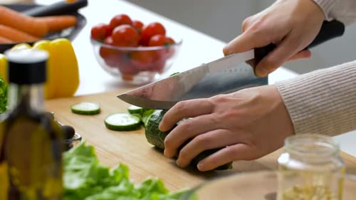 Hands Slicing Cucumber on Cutting Board