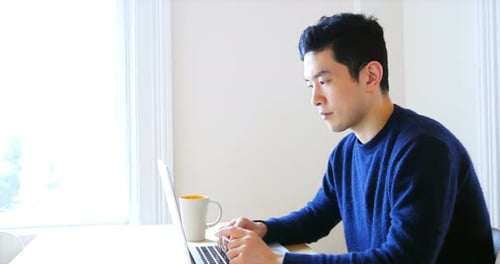 Man Types on Laptop in Bright Indoor Setting