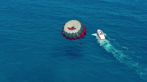 Luftaufnahme. Menschen, die auf einem bunten Fallschirm fliegen, der von einem Motorboot geschleppt wird. Parasailing im blauen Himmel.