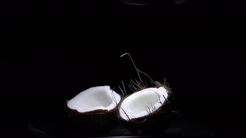 Cracked Coconut Halves Lit in the Darkness