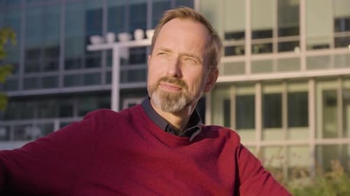 Man with Beard Sitting Outside Building Smiling