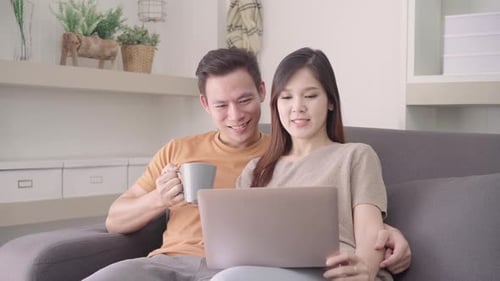 Happy Couple Laughing at Laptop on Couch