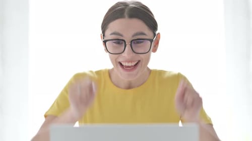 Woman Celebrates Success Using Laptop at Home
