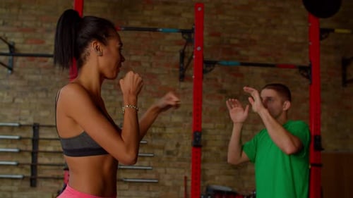 Athletic Woman Boxing with Trainer in Urban Gym