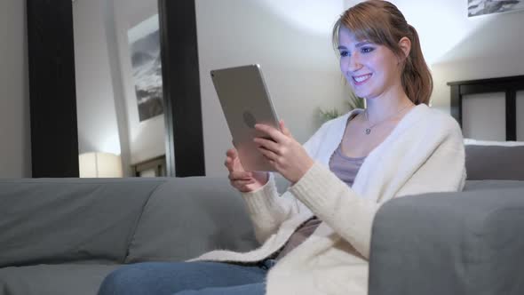женщина ищет видео на планшете в уютной комнате