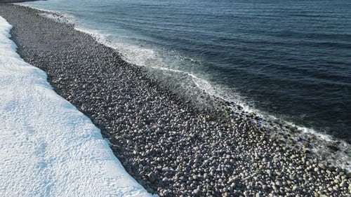 Winter Aerial Flight Top Over Waves Rolling on Artic Ocean Shore with Round Stones Ocean Waves at