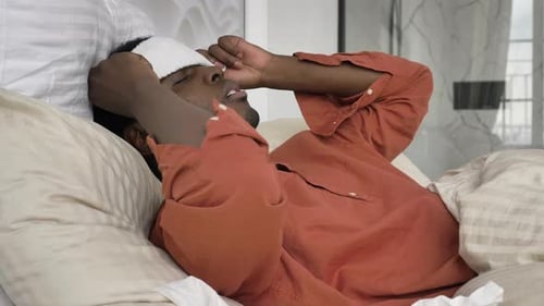 Homme afro-américain avec un patch sur les pilules pour la tête et un thermomètre