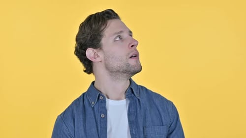 Man Looking Around in Surprise Against Yellow Background