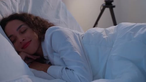 Latino beautiful woman lying down on bed sleeping alone in bedroom in dark night room at home.