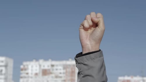 Raised Fist Against Blue Sky and Buildings