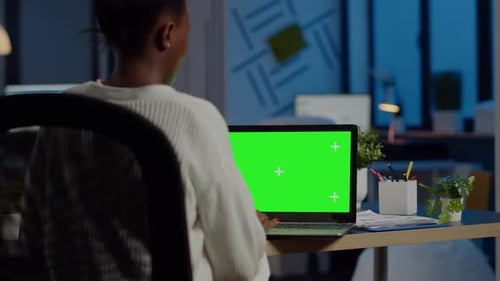 Young Adult Using Laptop with Green Screen in Office