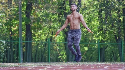 Muscular Man Jumps Rope for Fitness on Track