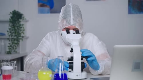 Lab Worker Inspects Specimen Under Microscope