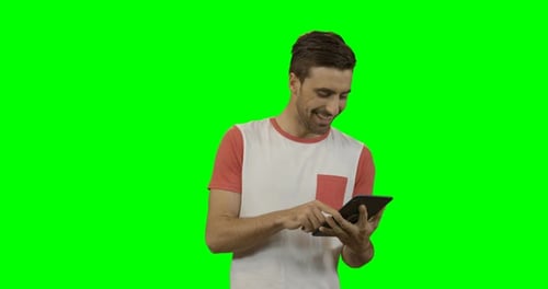 Young Adult Man Uses Tablet Against Green Screen